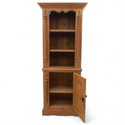 Contemporary stripped pine bookcase cabinet, the upper section with arched frieze and open shelving flanked by barley twist columns, over a single door cupboard base with matching twist supports and fielded panel door