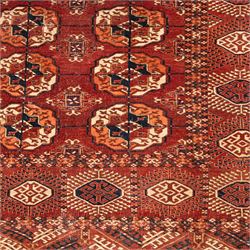 Persian Bokhara crimson ground rug, the field decorated with five rows of repeating Gul motifs with interspersed geometric design, enclosed by a guard band of further geometric-style Gul designs comprised of hook motifs