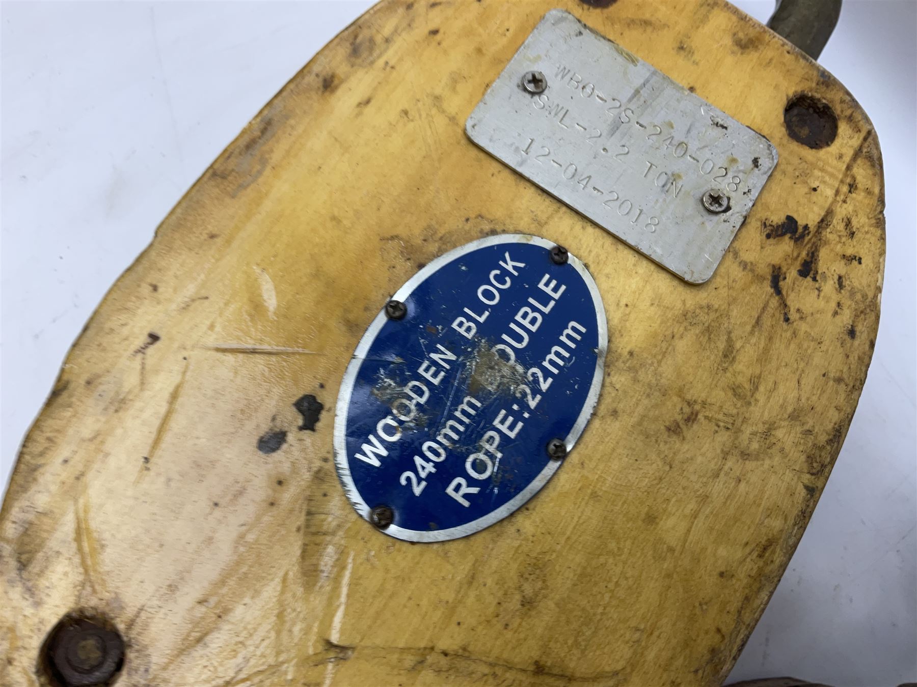 Three ship pulleys comprising wooden block double with swivel eye marked 'wooden block 240mm double rope: 22mm',  wooden block double with upset shackle and wooden block with stiff swivel hook, largest example L50cm