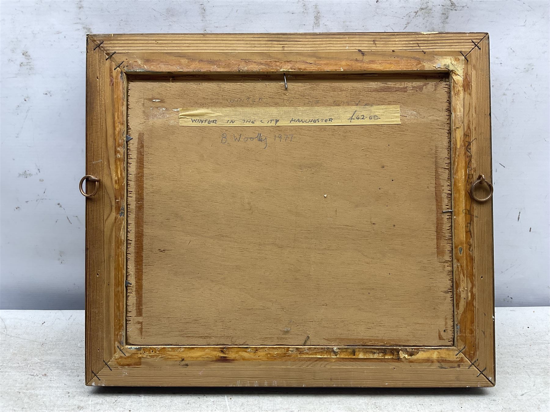 B Woolley (Northern British 20th century): 'Winter in the City - Manchester', oil on canvas laid on to panel signed and dated '77, 23cm x 28cm