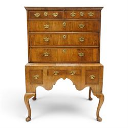 George II figured walnut chest-on-stand, the moulded cavetto top over two short and three long graduating cross-banded drawers, each fitted with pressed brass handle plates, the base fitted with three further drawers over a shaped apron, raised on cabriole supports with pad feet