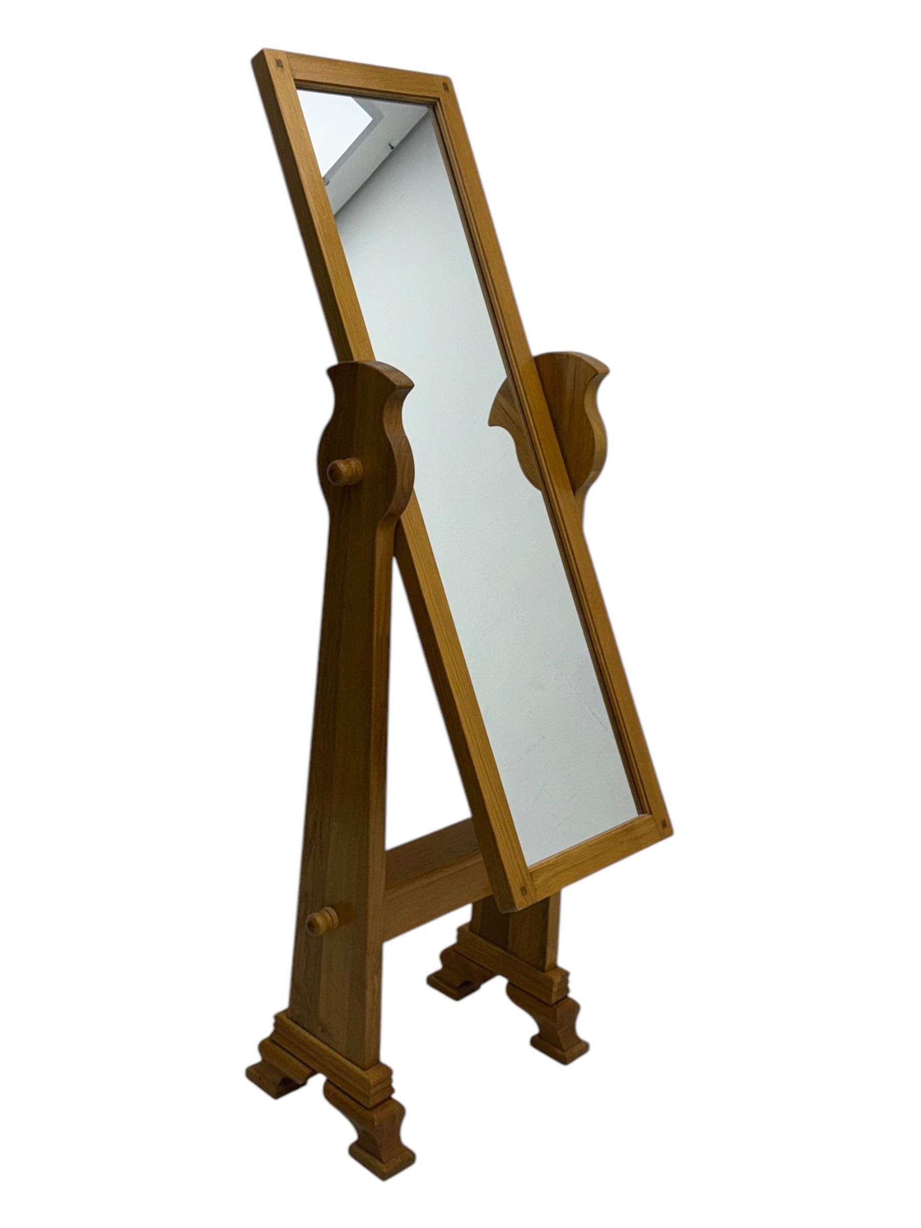 Contemporary light oak cheval dressing mirror, rectangular frame enclosing plain mirror plate, on shaped supports with turned finials, raised on stepped bracket feet