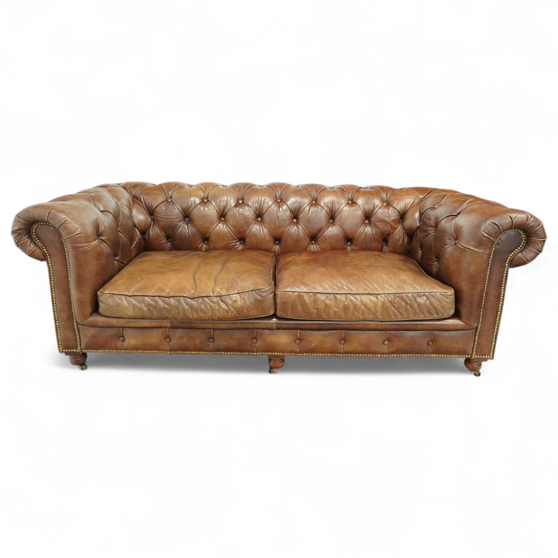 Timothy Oulton, Halo - Late 20th century brown leather Chesterfield settee, the upholstered frame with deep buttoning to back and arms, large scroll terminals with brass studwork, twin seat cushions, raised on castored legs