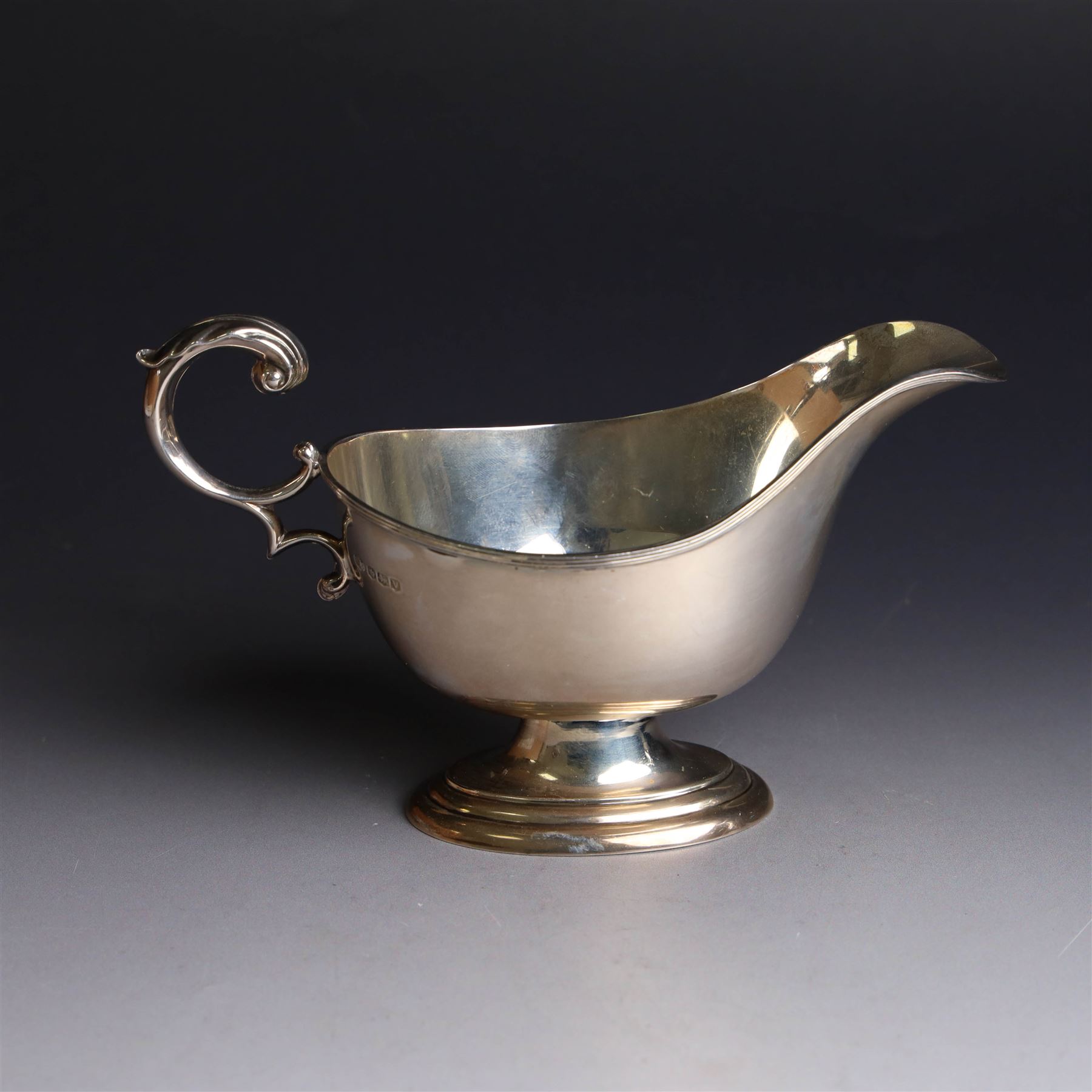 1930s silver sauce boat, of typical form with acanthus capped flying C scroll handle and upon stepped oval foot, hallmarked William Hutton & Sons Ltd, Sheffield 1938, height including handle H10cm