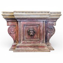 A 20th century Italian Neoclassical console table of monumental architectural form, inspired by Roman altar and sarcophagus prototypes; the rectangular marble top with dentil-moulded edge and polychrome geometric compass-star inlay, executed in contrasting marbles on a dark green ground, above a pedestal base of simulated stone finished in red porphyry-type tones, centred by a lion’s mask in relief and flanked by Ionic scroll volutes, raised on a stepped plinth base