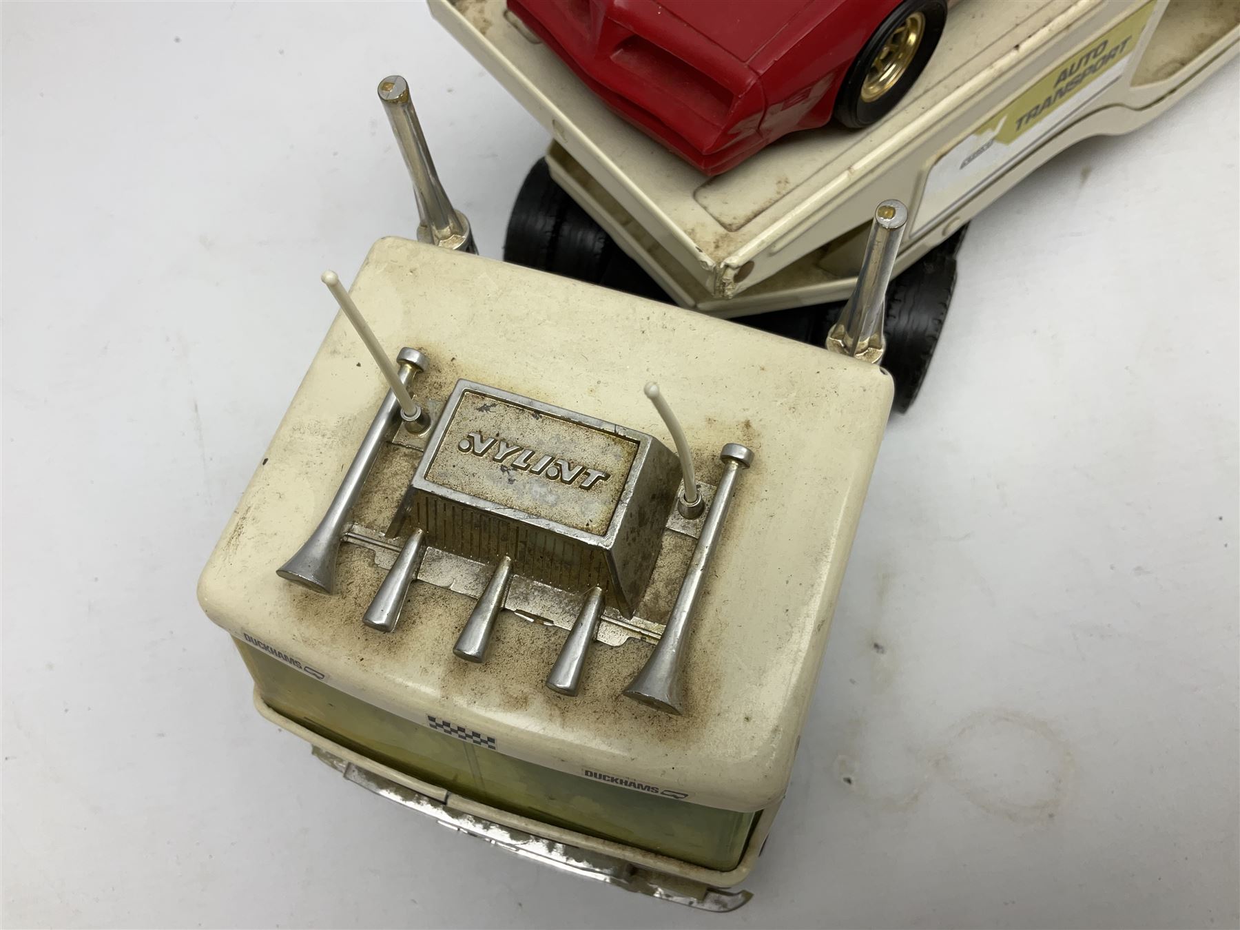 American Nylint large scale tin-plate car transporter L59cm carrying a Testor Toys plastic car; Tonka tin-plate mobile crane; boxed Sarony Cigarettes tin-plate roulette game with rules; and Japanese style tin-plate box, the lid inset with a revolving poker dice game (4)