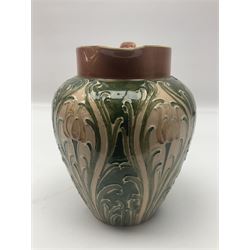 Moorcroft Macintyre Burslem jug, circa 1902, decorated with a motif of stylised flowers amongst scrolling foliage, in shades of brown and green on a peach ground, with printed mark beneath, H16cm