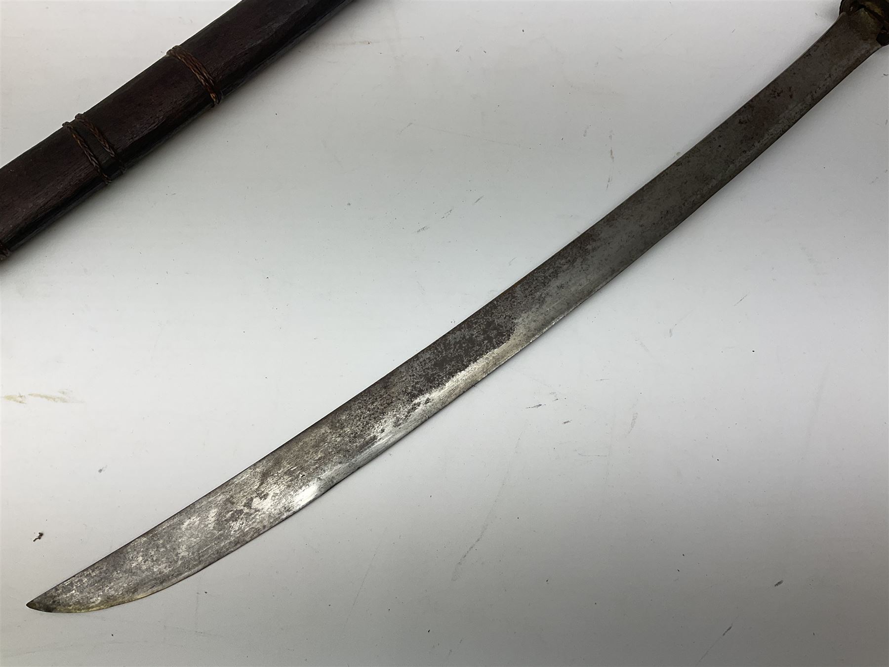 Burmese Dha type sword with 52cm plain steel slightly curving blade and plaited cane bound grip; in wooden scabbard with plaited cane bands L76.5cm overall