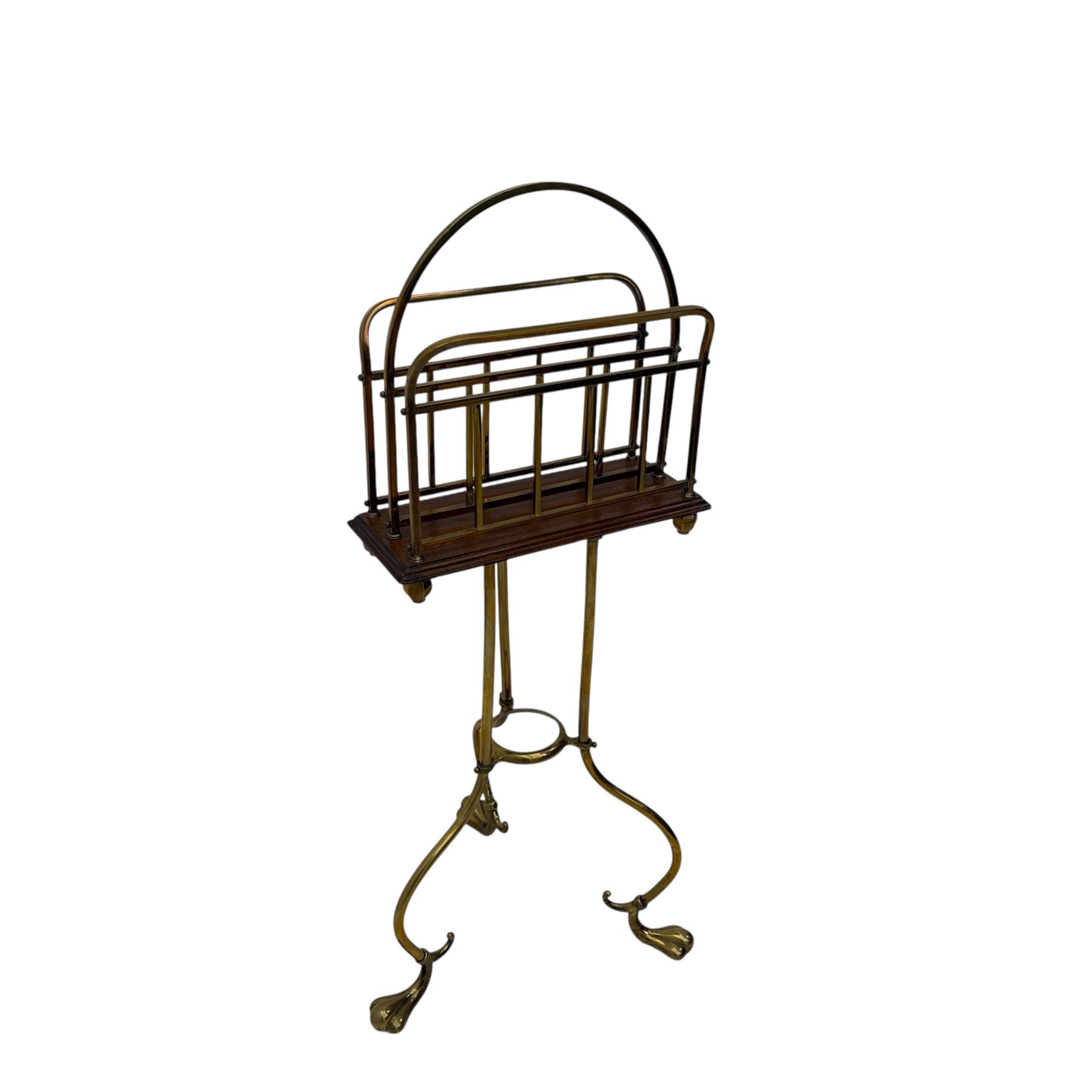 Edwardian oak and brass revolving magazine stand, arched frame with slatted slides and oak base, mounted on a brass column supported by three stylized scrolling legs terminating in pad feet