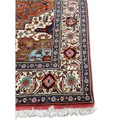Large Persian carpet, the geometric and stylised floral medallion on rust ground field decorated with stylised plant motifs, guarded ivory border with repeating pattern
