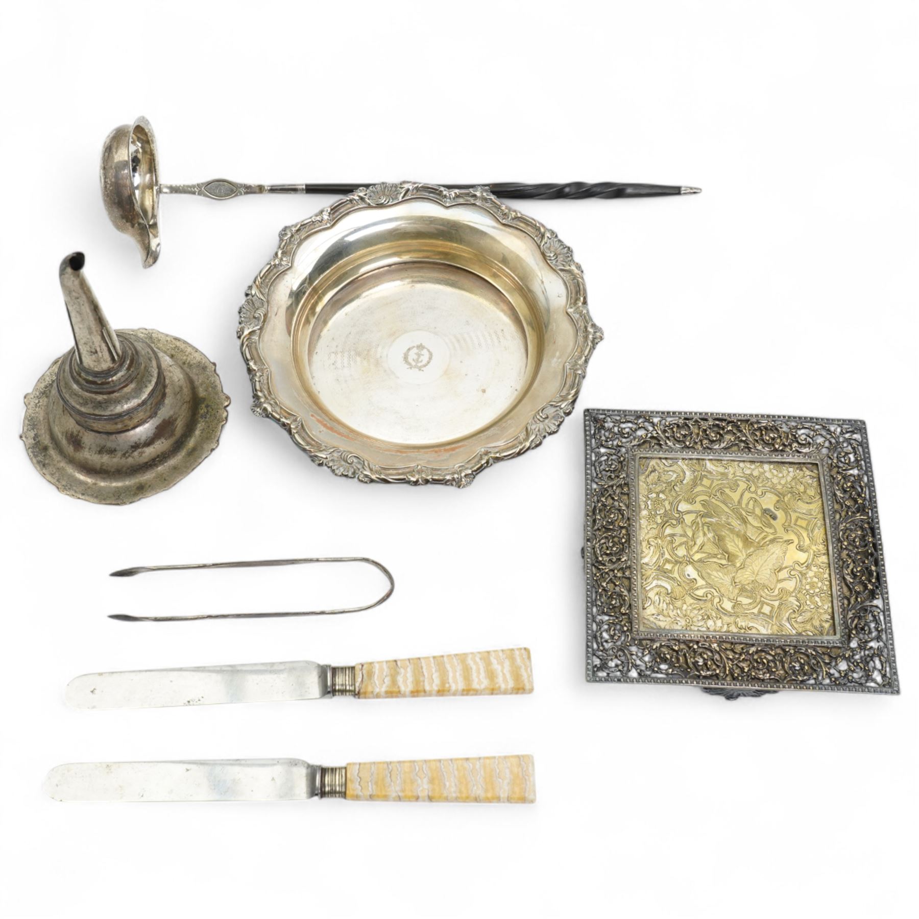 Early 19th century silver punch ladle, the bowl inset with a George III coin and with twisted whale bone handle,, plated wine funnel, two knives by John Wigfall, Sheffield with mammoth tooth handles, plated coaster with engraved crowned anchor crest, teapot stand with brass centre and plated surround and a pair of sugar tongs  