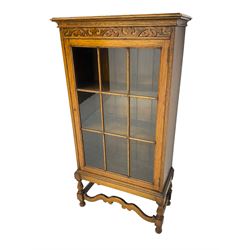 Early 20th century oak bookcase display cabinet, enclosed by single glazed door, on turned supports with shaped front stretcher rail