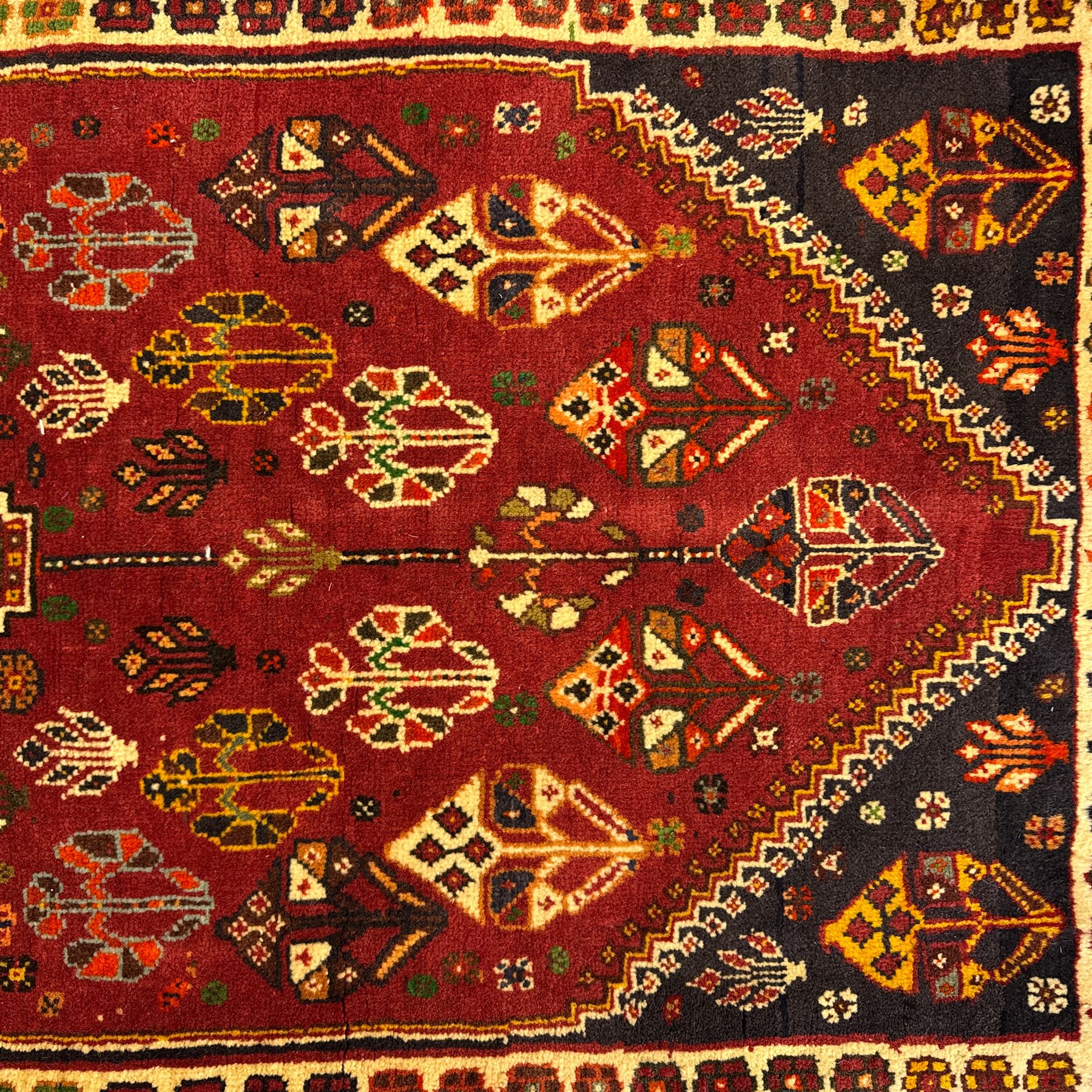South West Persian Qashqai rug, hand knotted wool with central dark blue lozenge medallion containing geometric motifs, on a madder red field decorated with stylised floral boteh motifs, indigo spandrels, multiple borders of floral rosettes, from the region of Fars, south-west Persia