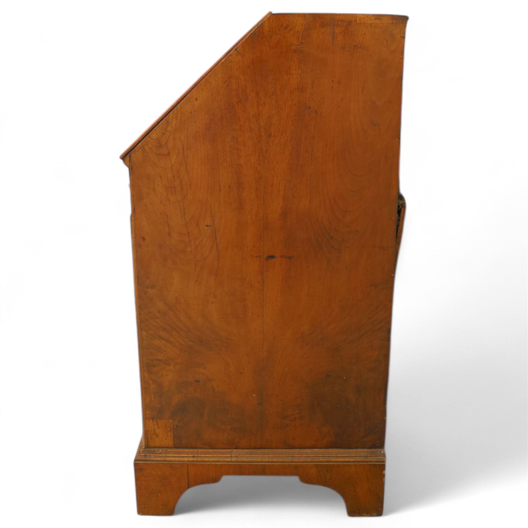 18th century walnut and herringbone banded bureau, the fall front enclosing a stepped and arched interior fitted with pigeonholes, drawers and concealed compartments, green tooled leather writing surface, over two short and three long graduated drawers with brass escutcheons and bail handles, shaped bracket feet