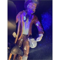 Mid 18th century Furstenberg figure, modelled as a beggar or mendicant with peg leg and bare foot, circa 1755, modelled by Simon Feilner, wearing tattered clothes, one arm supporting an alms pouch, the other holding a crutch, upon a part scrolled base, bearing paper labels beneath including one inscribed 'Sammlung Wilhelm Gumprecht 322', H15cm