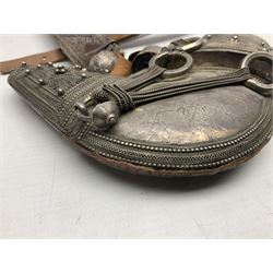 Omani Khanjar dagger, the 19cm curved blade with pronounced medial rib to either side, waisted hilt with dome shaped pommel and silver covered horn grip decorated with filigree bands, floral motifs and beadwork; in an intricately filigree decorated silver and leather scabbard with silver rings woven into the belt mount and fitted with original silver thread-work belt L34cm overall belt length 94cm