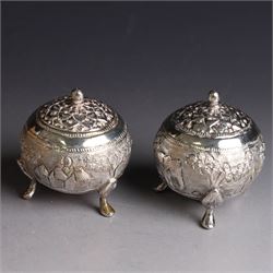 Pair of Middle Eastern silver cruets, of spherical form with pierced tops, embossed with figures, elephants and village scenes, unmarked, together with a pair of silver condiment spoons embossed with floral decoration 