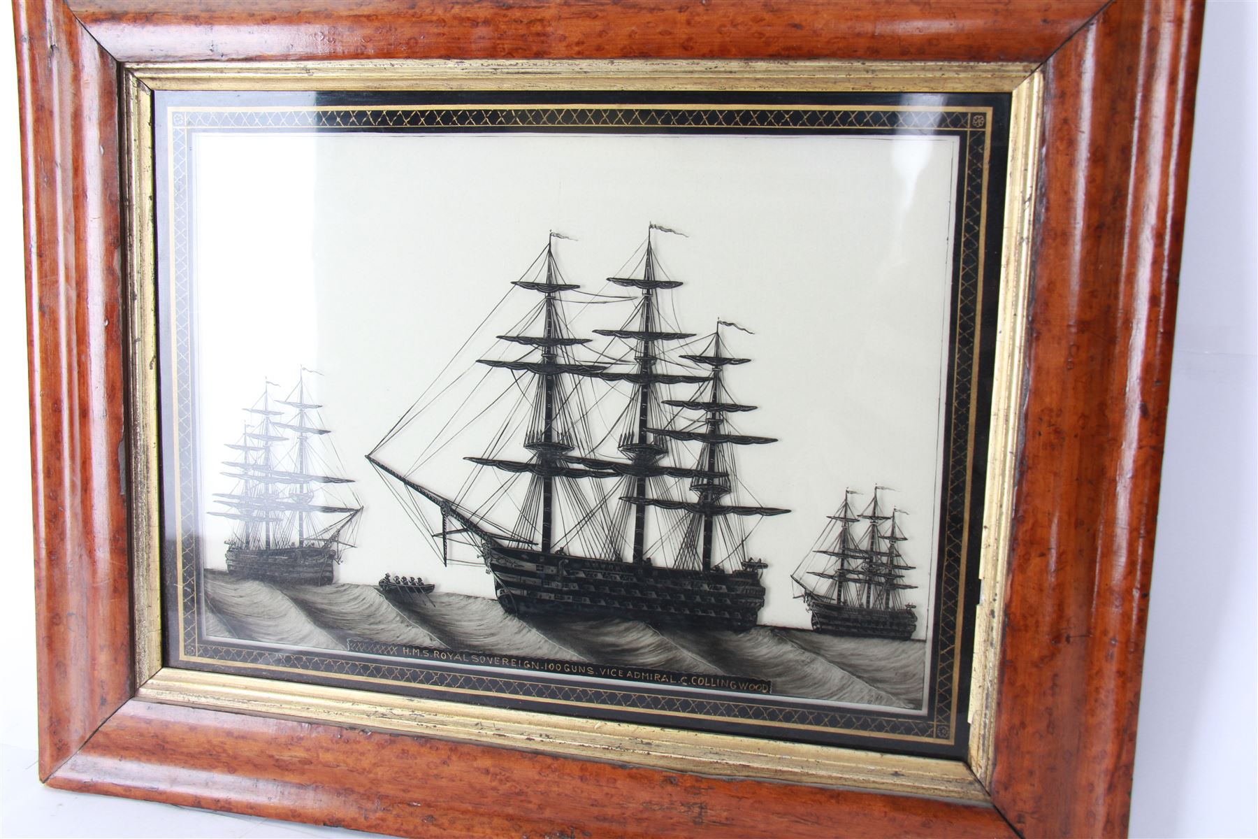 19th century monochrome ship silhouette, reverse painted on glass, within Verre Eglomise border inscribed 'HMS Royal Sovereign 100 Guns Vice Admiral C.Collingwood', in a birds eye maple frame, painting H31cm, W41cm