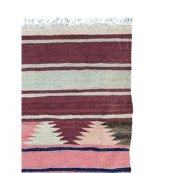 Kilim muted pink ground runner, decorated with rows of horizontal bands in muted tones, alternating with geometric triangular patterns along each band, fringed ends