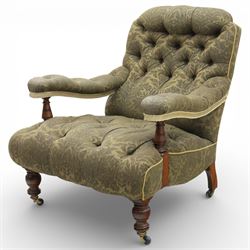 Late Victorian open armchair, in the manner of Howard & Sons, with deep buttoned seat and back upholstered in green damask fabric, with fringed detail to the lower arms, raised upon turned front legs with brass castors