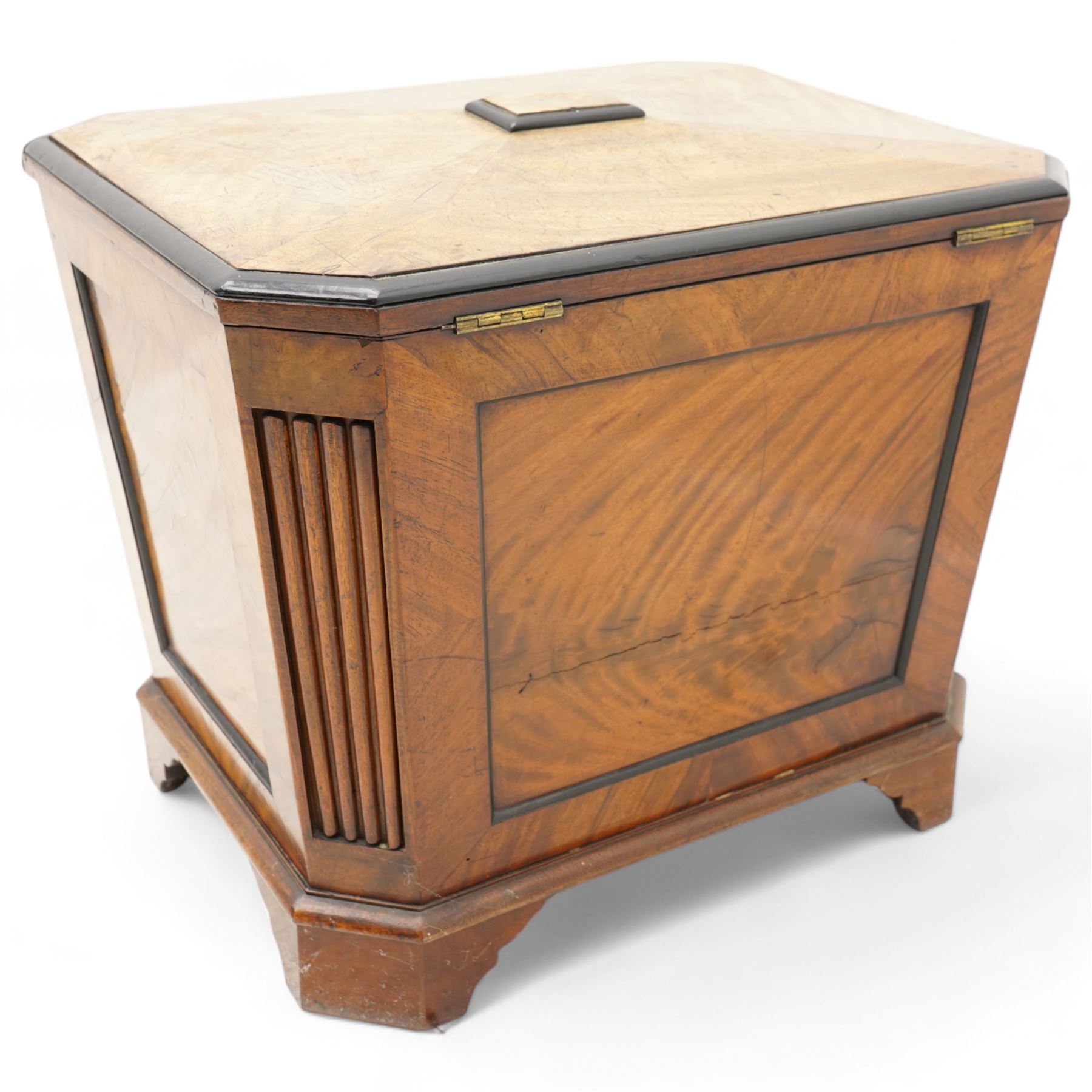 Early 19th century mahogany cellarette, tapering canted rectangular form, the hinged faceted top enclosing fitted interior, panelled front, back and sides with figured mahogany veneers, the canted corner with wide reeded decoration, on canted bracket feet 