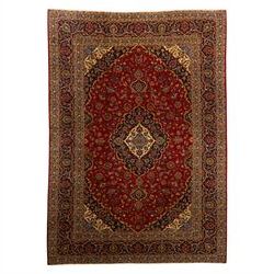 Central Persian Kashan hand-knotted carpet, crimson ground, with a central shaped palmette...