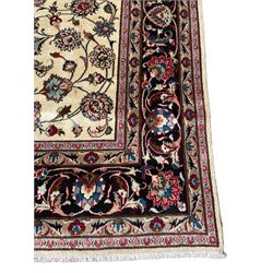 Persian ivory ground rug, the field decorated with interlaced and scrolling foliate with palmettes, the dark indigo border with stylised plant motifs surrounded by scrolled branches