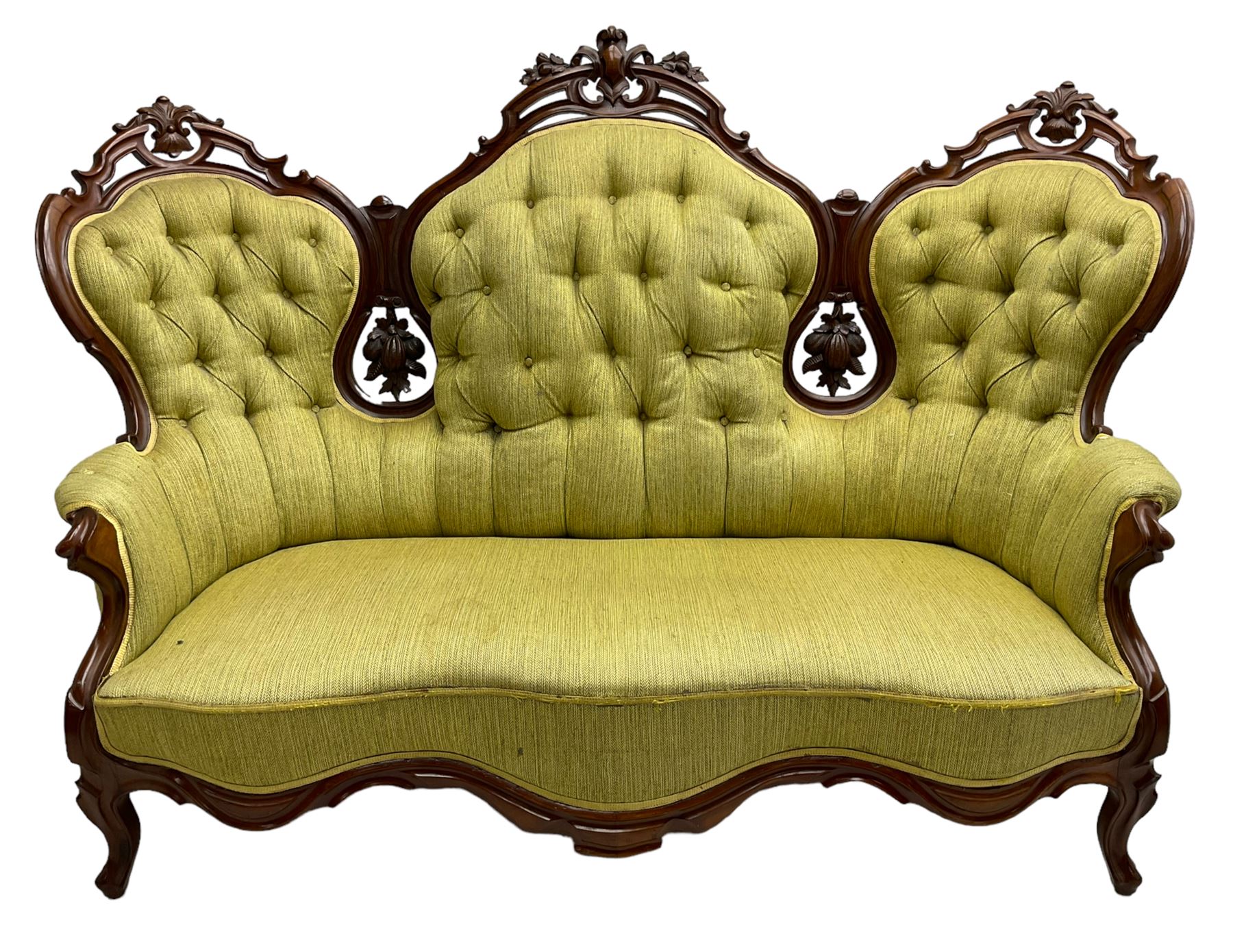 Victorian walnut settee, triple back with pierced and scroll-carved cresting rails over carved fruit and foliage decoration, upholstered in buttoned green fabric, serpentine seat and carved apron, on cabriole feet