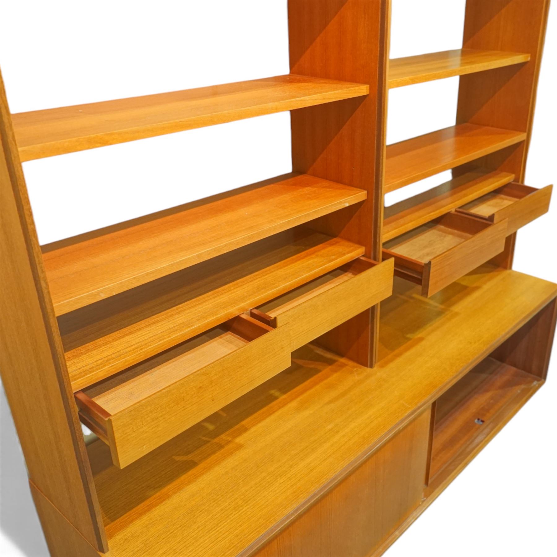 G Plan - 'Form 5' teak modular bookcase unit, comprising two upright sections with upper cupboard compartments enclosed by hinged doors, open adjustable shelving below, fitted with a pair of central drawers to each section, raised over a long base cabinet with sliding cupboard doors