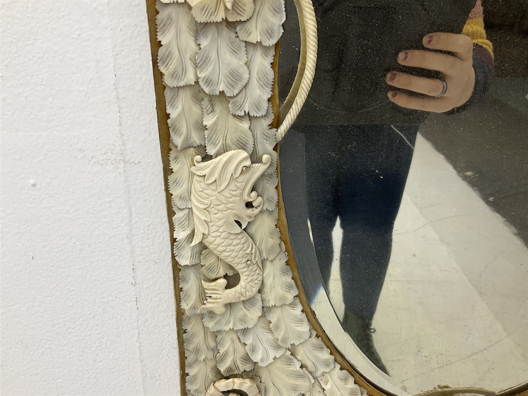 Pair 19th century French Dieppe bone and ivory wall mirrors, the oval bevelled mirror plates within rectangular frames with shaped tops, profusely decorated with ivory leaves, further detailed with carved bone armorial type crest inscribed 'SGOTORVM', putti, fish and mask heads, H81cm W48cm