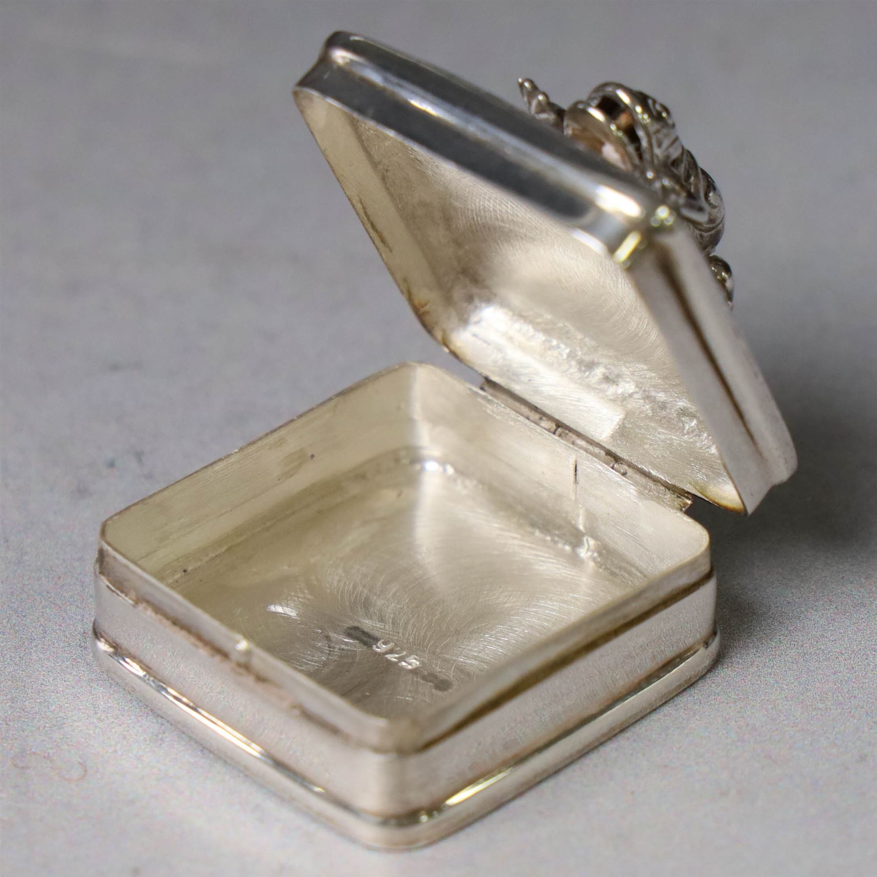 Modern silver pill box, of square form, the hinged cover surmounted with figure of a frog within a engraved scroll edge, hallmarked hallmarked Martin Gerald & Sid Adler, London 2000, W3cm