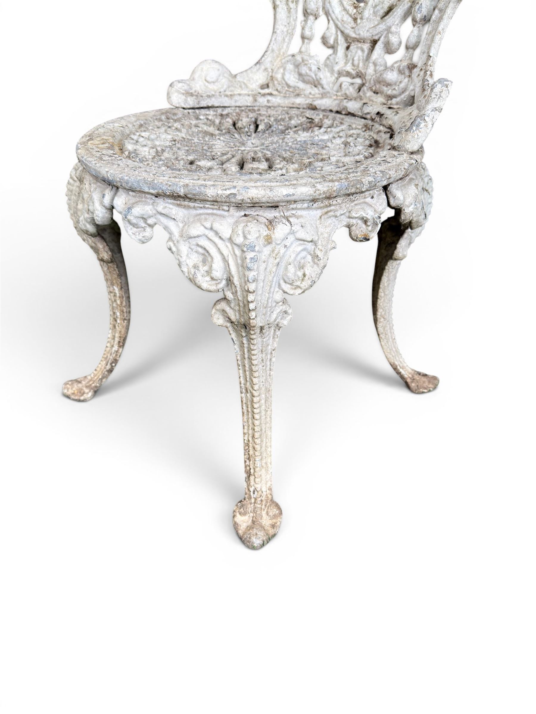 Pair of white painted cast metal garden chairs, ornate reclined backs, circular pierced seats on cabriole legs