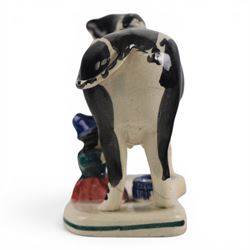 Three Staffordshire cow creamers, one with treacle glaze, the other two painted black and white with a seated figure of a milkmaid, H14cm