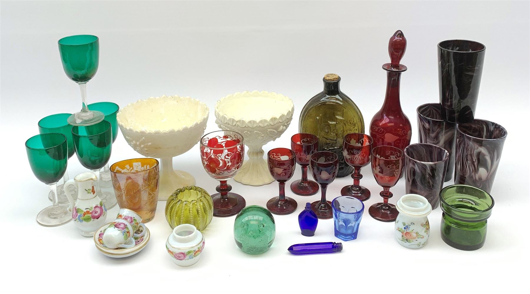 A group of Victorian glassware, to include Ruby flashed decanter and six glasses, decanter H25cm, five further drinking glasses with green bowls, a dump paperweight, and miniature painted milk glass teawares, two slag glass pedestal bowls, four slag glass tumblers, plus a small selection of later glassware, comprising a moulded glass bottle detailed 'Success to the Railroad', and an amber glass Isle of Man 1892 exhibition compressed tumbler. 