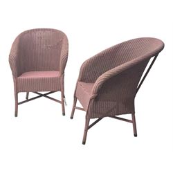 Pair of Lloyd Loom design tub chairs, each with woven wicker construction, curved backrests and painted in a soft pink finish, on cylindrical supports with X-stretchers