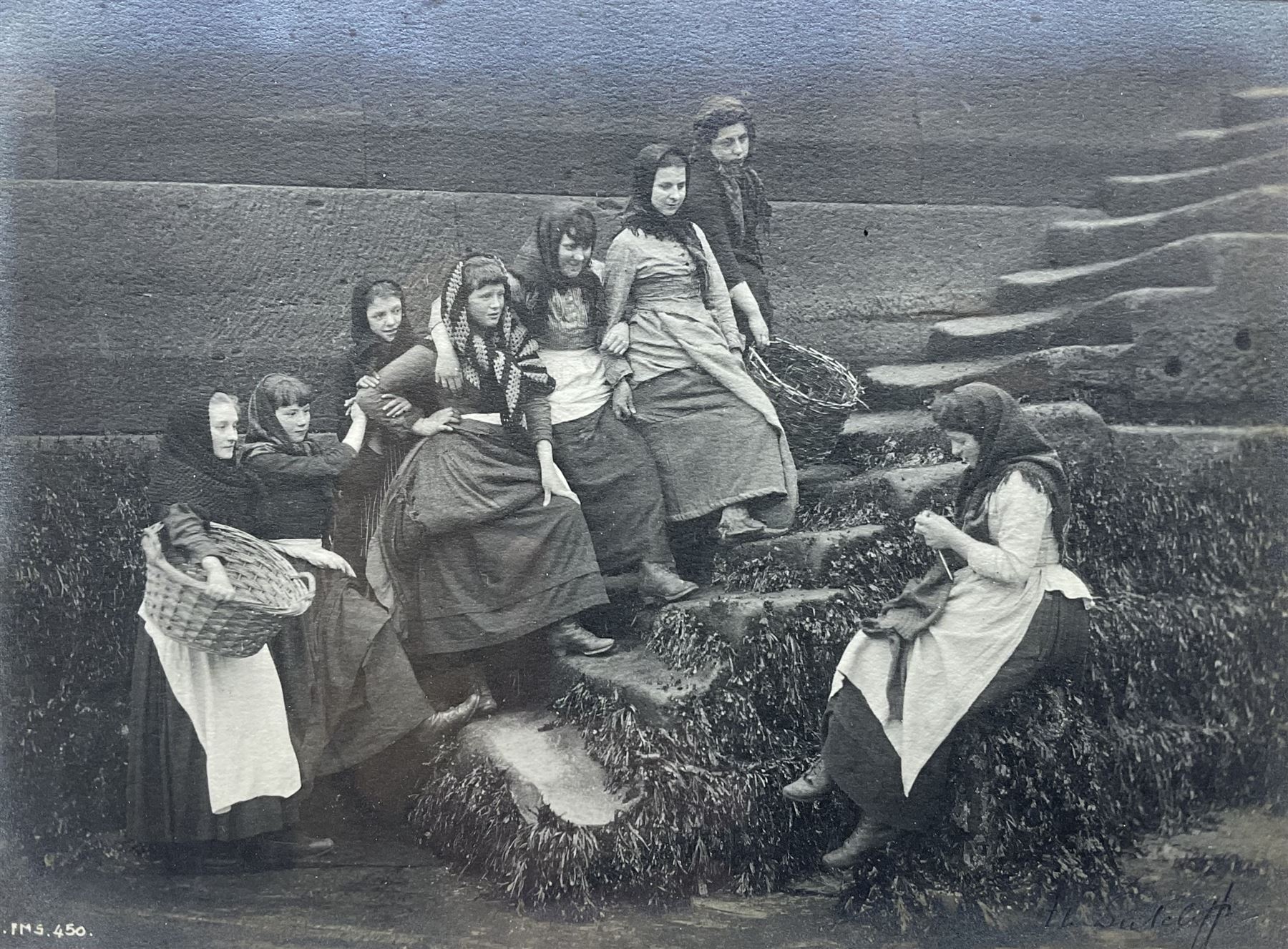Frank Meadow Sutcliffe (British 1853-1941): Eight Fishergirls at the Foot of Whitby East Pier (E-6C), photograph signed in pencil, initialled and numbered FMS 450 in the image, original  FM Sutcliffe Whitby label verso 14cm x 19cm