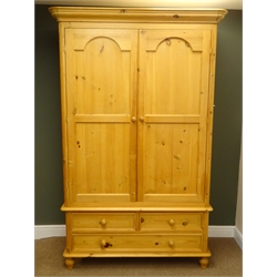  Solid pine double wardrobe, projecting cornice, two doors enclosing hanging rail above tow short and one long drawer, turned supports, W135cm, H209cm, D62cm  