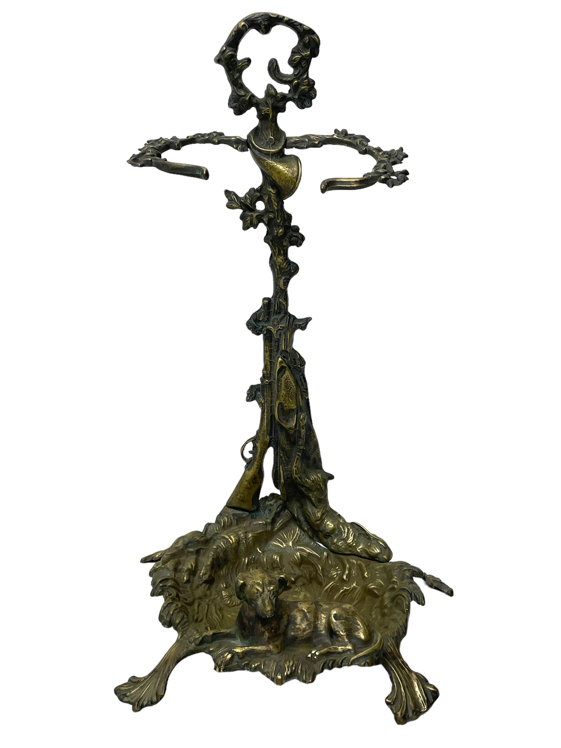 Pair of cast brass hallway umbrella or stick stands, in the form of a tree decorated with trailing flowering foliage branches, the stem with hunting horn over leaning shotgun, shaped naturalist tray base with hunting hound and out splayed foliate cast feet 