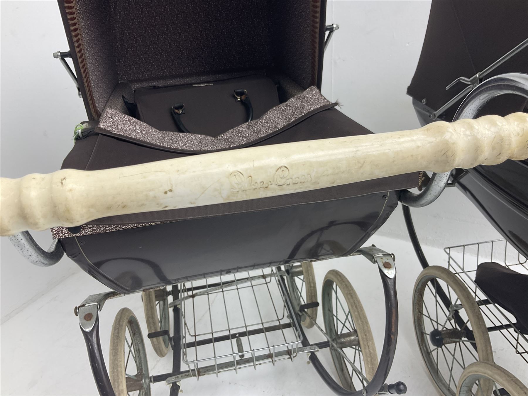 Pair of 1980s Silver Cross brown coach built dolls prams; each with folding canopy and apron, tubular framework with suspension, spoked wheels with brake and luggage rack and separate matching shopping bag L93cm