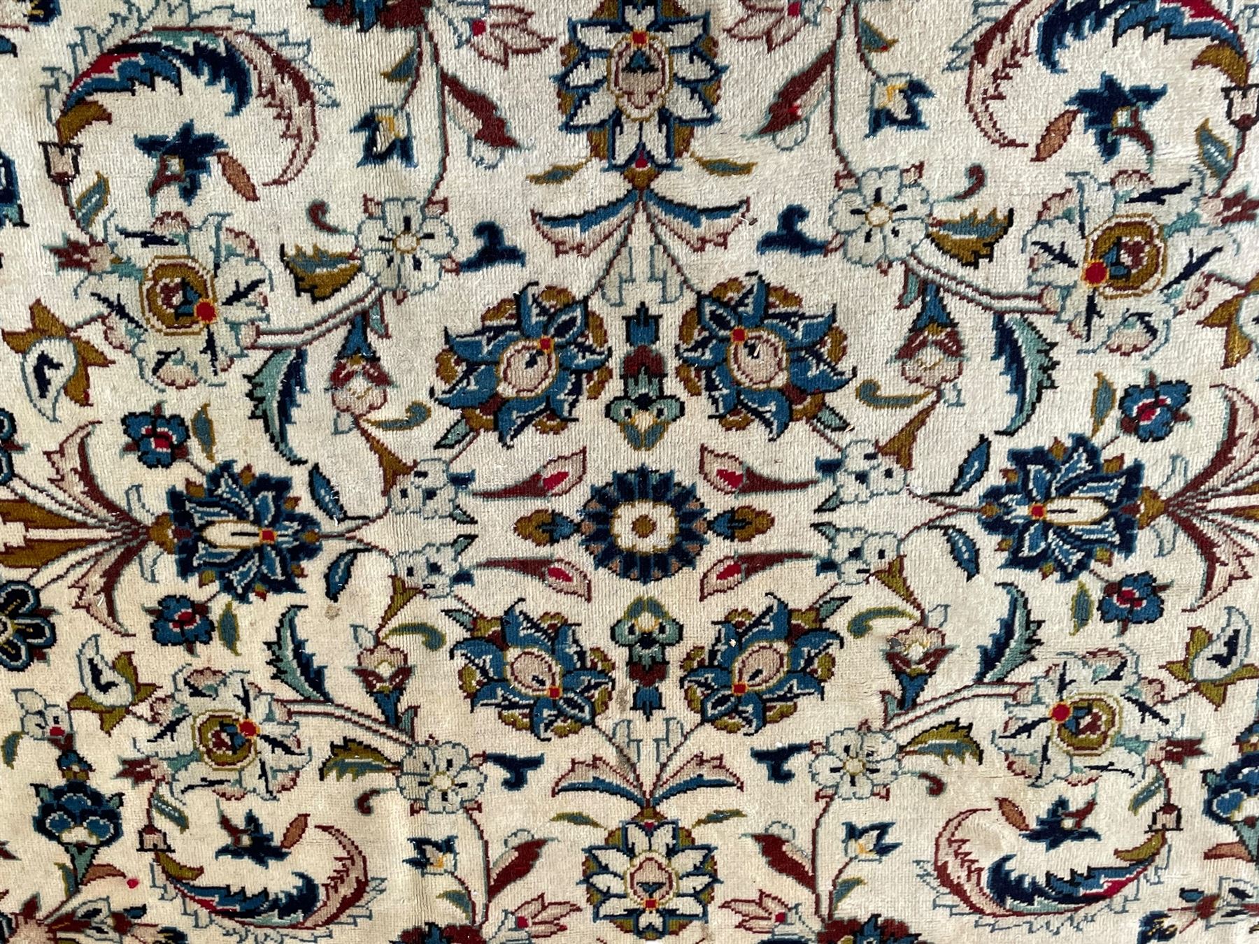 Persian Kashan ivory ground carpet, the field decorated with scrolling branches with foliate and palmette motifs, repeating border with stylised plant motifs, within floral and geometric pattern guard stripes 