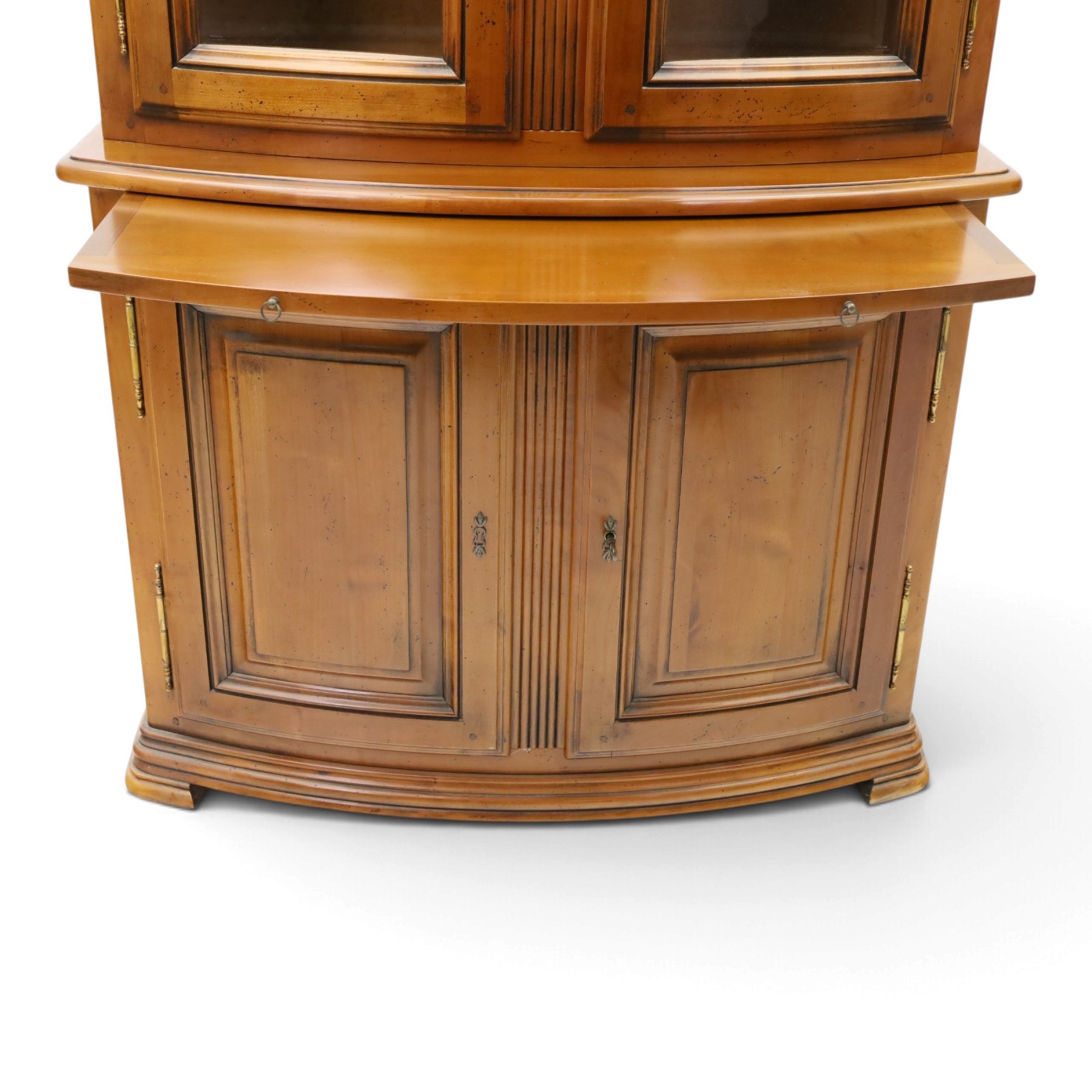 Wesley Barrell - French cherry wood bow front display cabinet, the upper section with glazed doors and three adjustable shelves, raised on cupboard base with brushing slide and further adjustable shelf, raised on a moulded plinth base with bracket feet