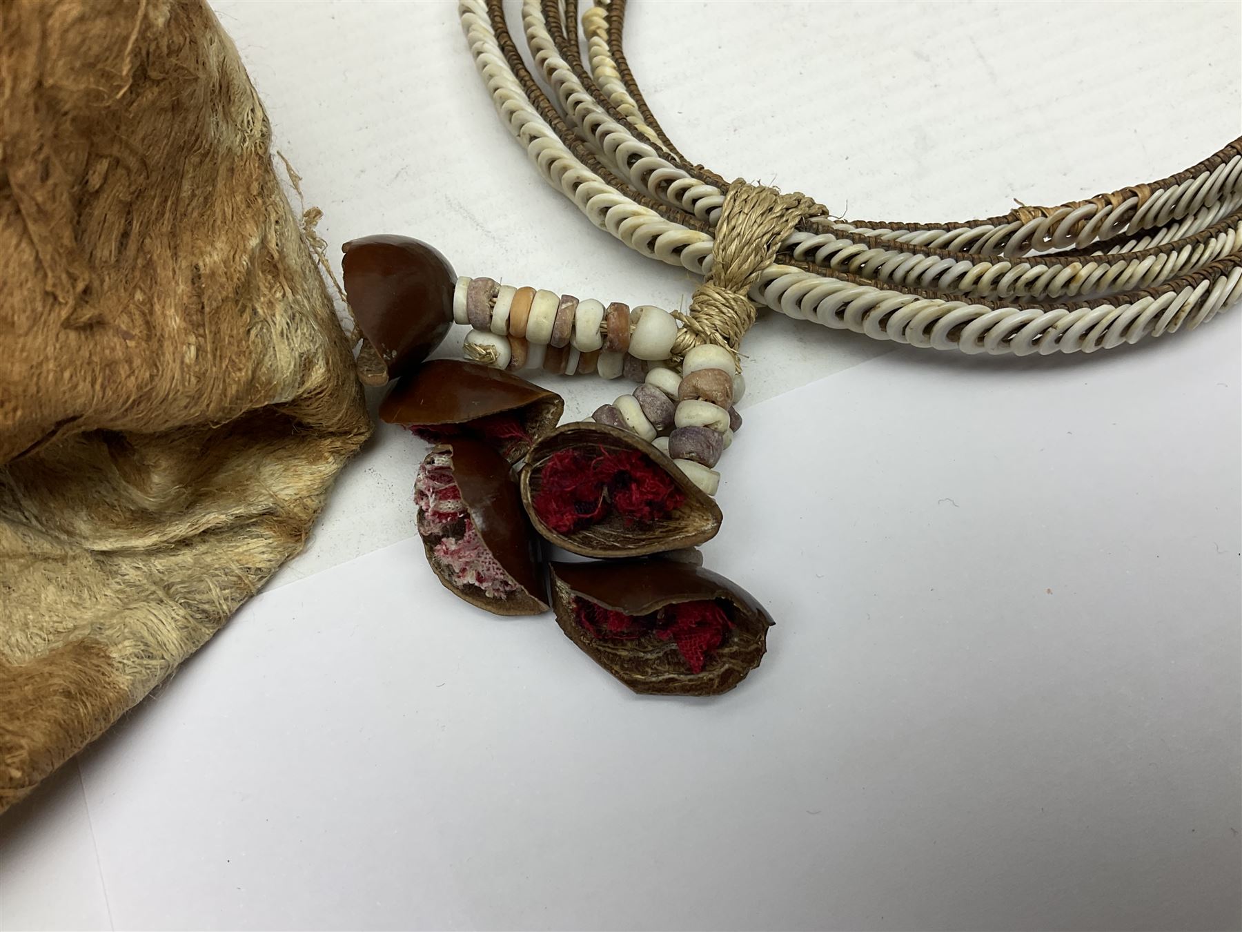 Collection of traditional necklaces from the Solomon Islands, including shell and boar tusk examples, together with a carved canoe prow, with mother of pearl eyes, painted cow hide and a copper plaque, depicting the Solomon Islands, with presentation engraving