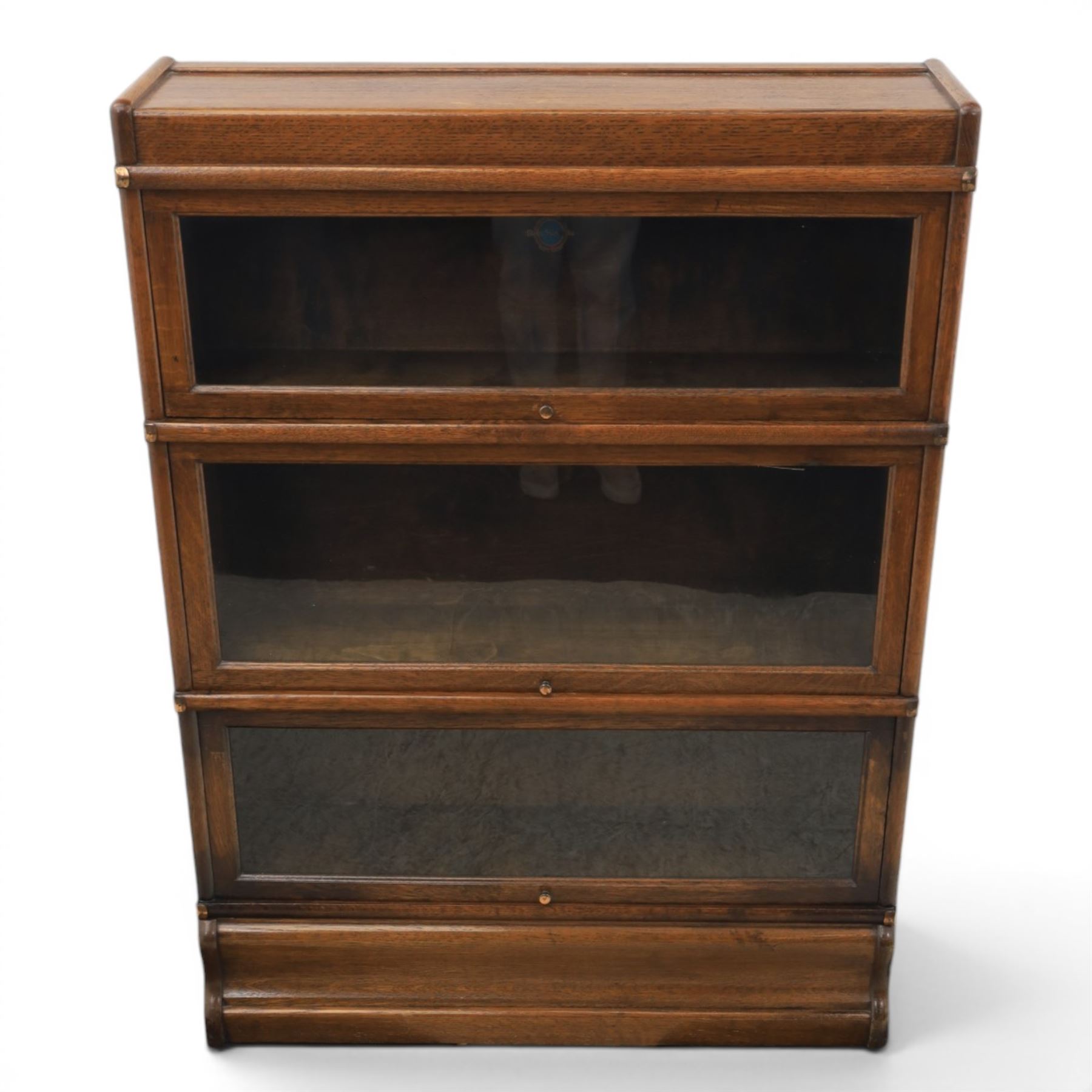 Globe Wernicke - early 20th century oak stacking bookcase, three tiers, lift up glazed doors raised on a plinth base