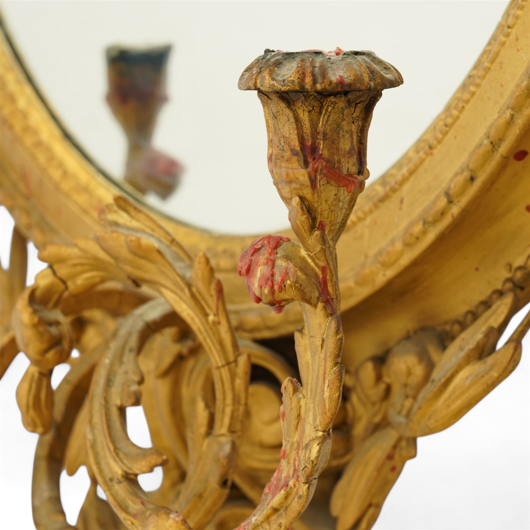 Late 19th century Louis XVI style giltwood and gesso girandole oval wall mirror, the oval frame surmounted with stylized urn finial and ribbon-tied garlands, laurel swags and rosettes, egg and dart decorated inner moulding and linked acorn outer moulding, flanked by intertwined foliate decorated candle branches 