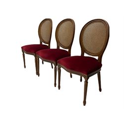 Set six French style walnut finish dining chairs, oval cane bergere backs over serpentine seats upholstered in red, flower head carved fluted supports