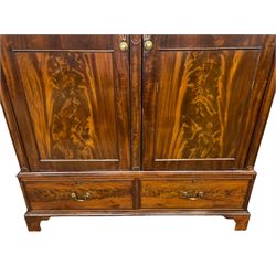 George III mahogany double wardrobe, the projecting cornice with dentil moulding over two panelled doors with mirror-lined interiors, enclosing hanging rails and brass hooks, the base fitted with two drawers, raised on bracket feet