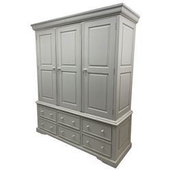 White painted triple wardrobe, projecting moulded cornice over three panelled doors, the interior fitted with hanging rails, four drawers and hinged cupboard to base, on bracket feet