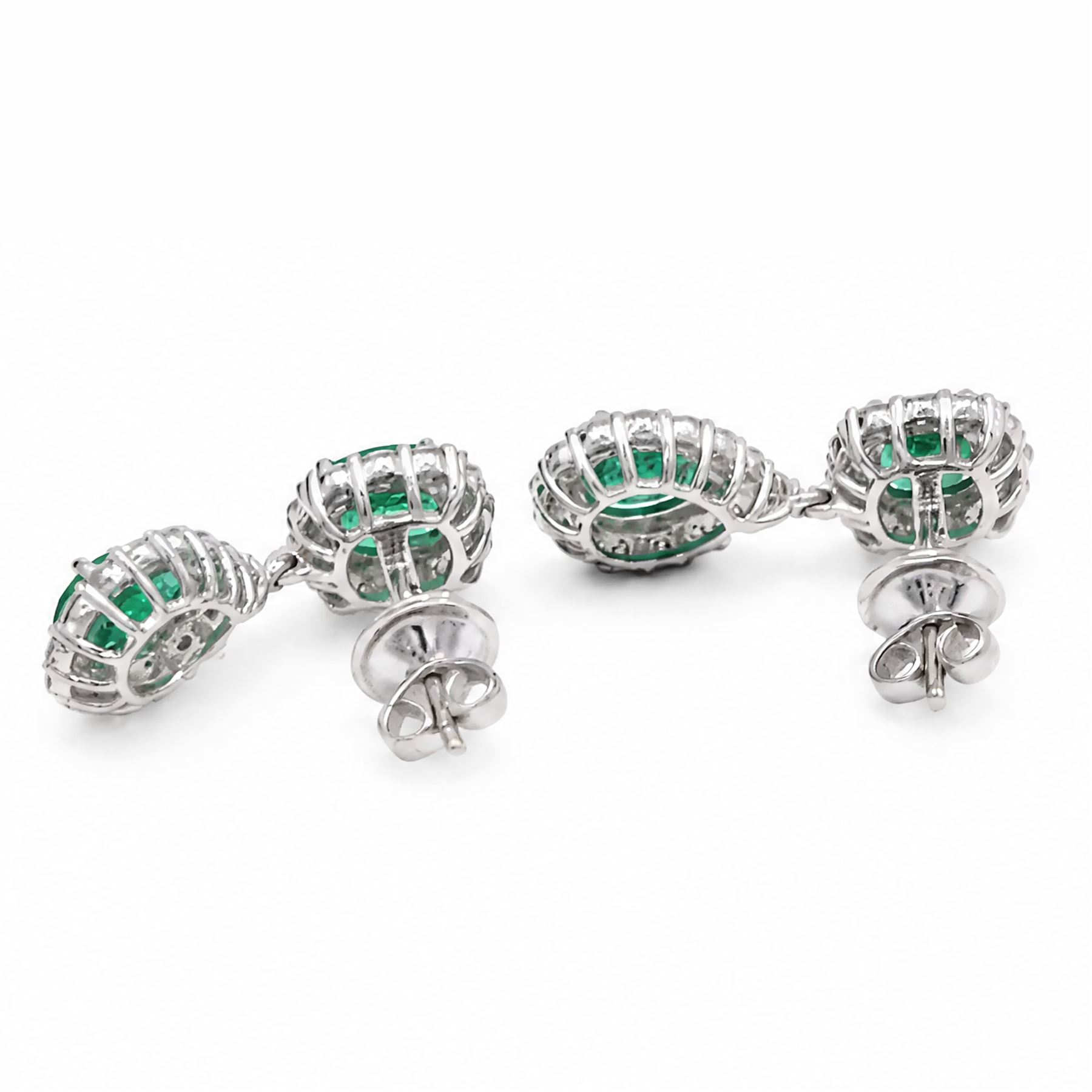 Pair of 18ct white gold emerald and diamond pendant earrings, each stud set with a cushion cut emerald and round brilliant cut diamond surround, suspending a further pear cut emerald and diamond cluster stamped, total emerald weight approx 3.45 carat, total diamond weight approx 1.70 carat