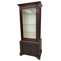 Mahogany display cabinet with hidden compartment, projecting cornice over single glazed door enclosing glass shelves, double panelled cupboard below, the interior with button releasing sliding back compartment, on bracket feet