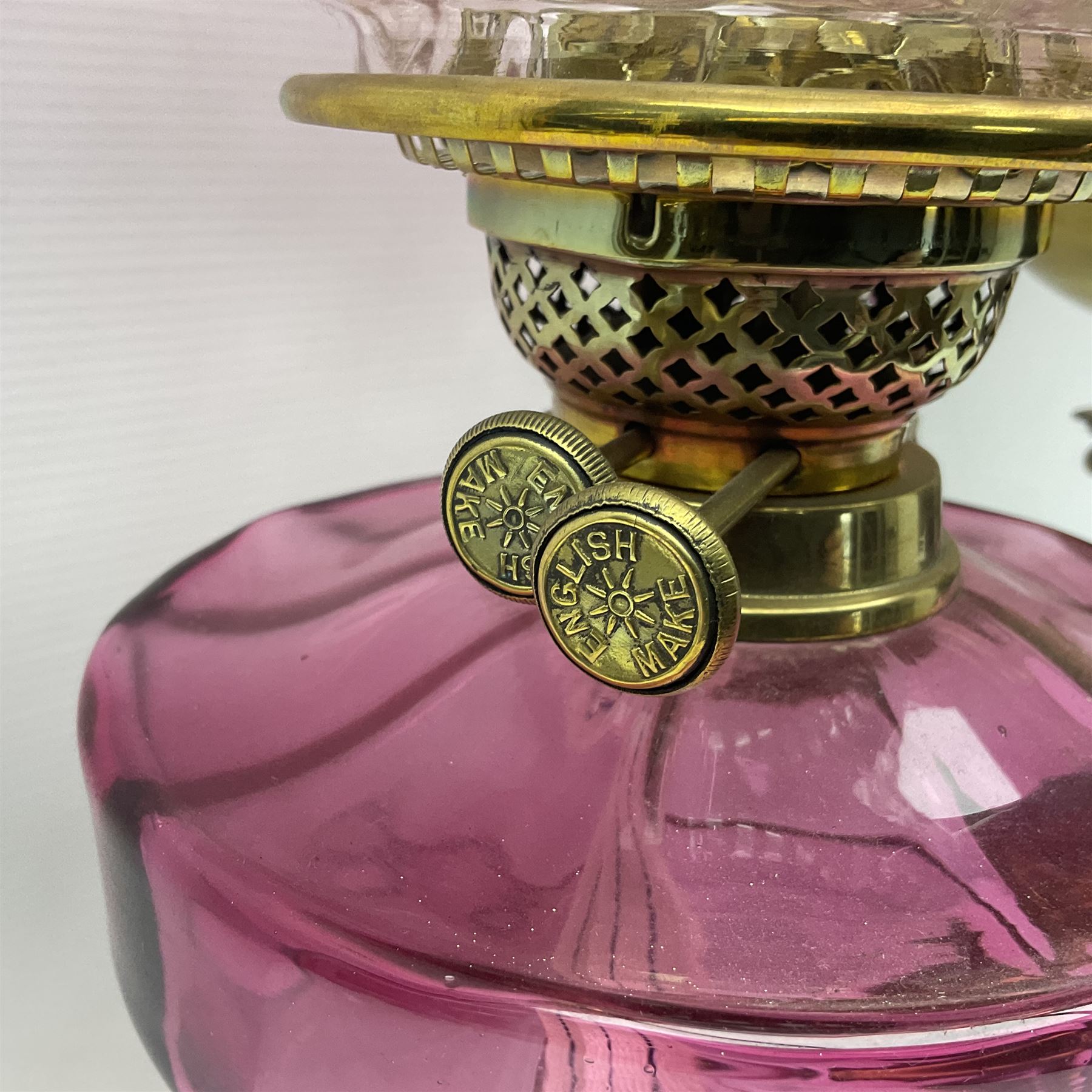 Victorian cast brass oil lamp, with fluted pink glass shade, together with two smaller brass oil lamps with pink shades and reservoirs and a pair of oil lamps, the bases modelled as putti, with pink glass reservoir  and frosted shades, tallest H70cm